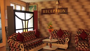 A reception area with a sofa set, a round table, and a 'RECEPTION' sign on the wall. - Jayaraj Residency (Kodaikanal)