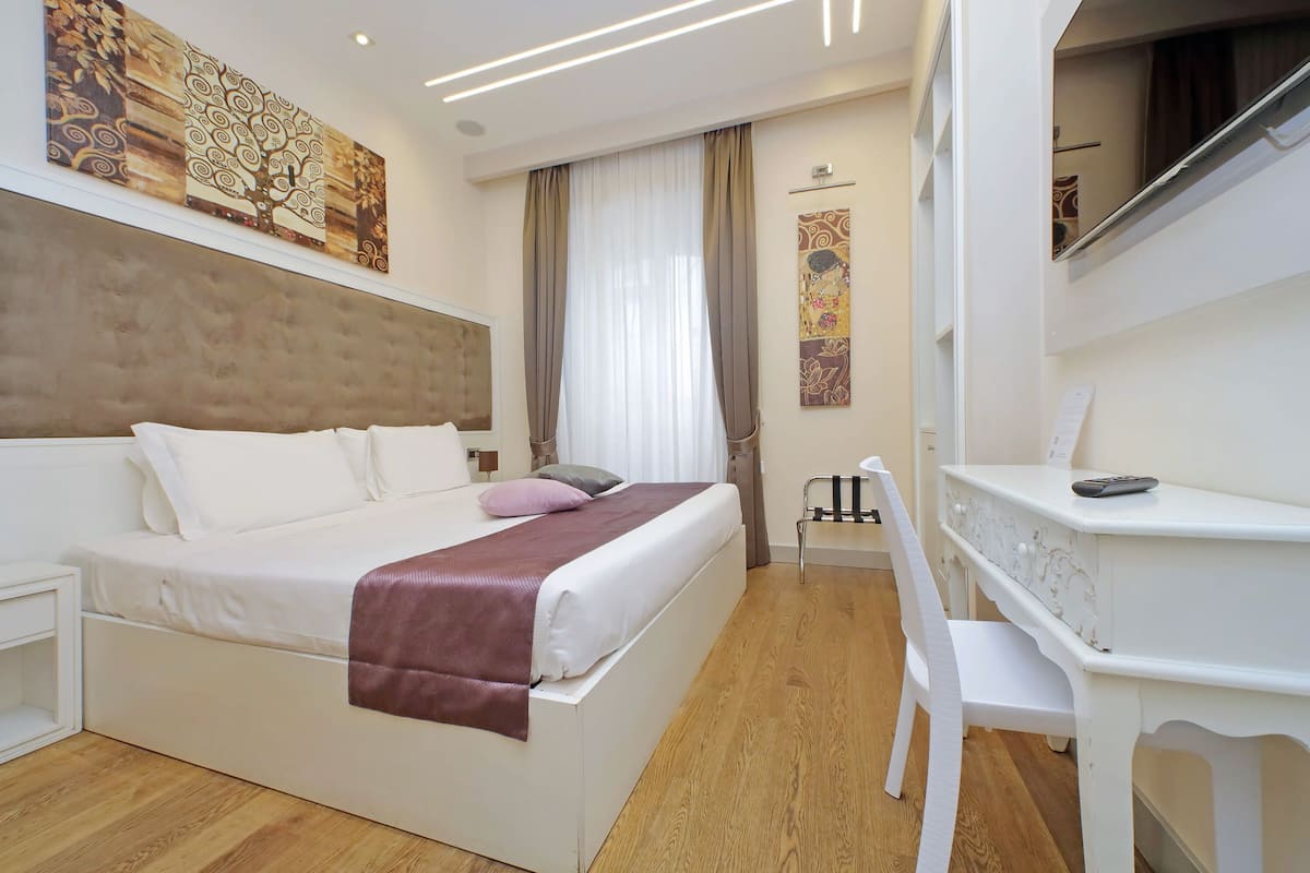 Una habitación de hotel con una cama, un escritorio y una silla.