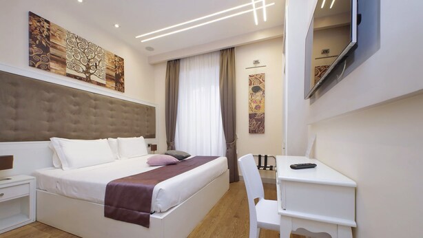 A modern hotel room with a large bed, a desk, and a chair. - alla locanda Malandra (Rome)