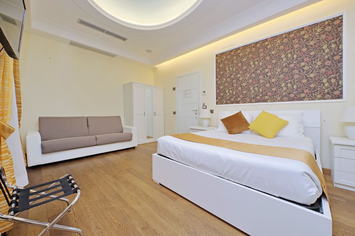 Un dormitorio moderno con cama, sofá, sillón y armario.