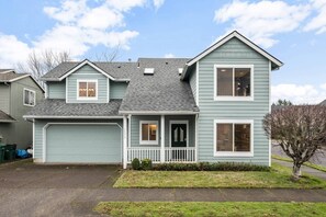 A two-story house with a front porch, garage, and a small front yard.