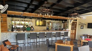 A bar area with a counter, bar stools, and a seating area with tables and chairs. - Alona's Coral Garden Resort  (Panglao)