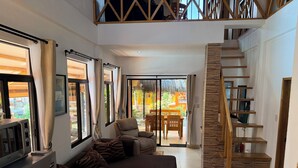 A spacious living area with a sofa, a coffee table, a TV, and a staircase leading to an upper level. - Alona's Coral Garden Resort  (Panglao)
