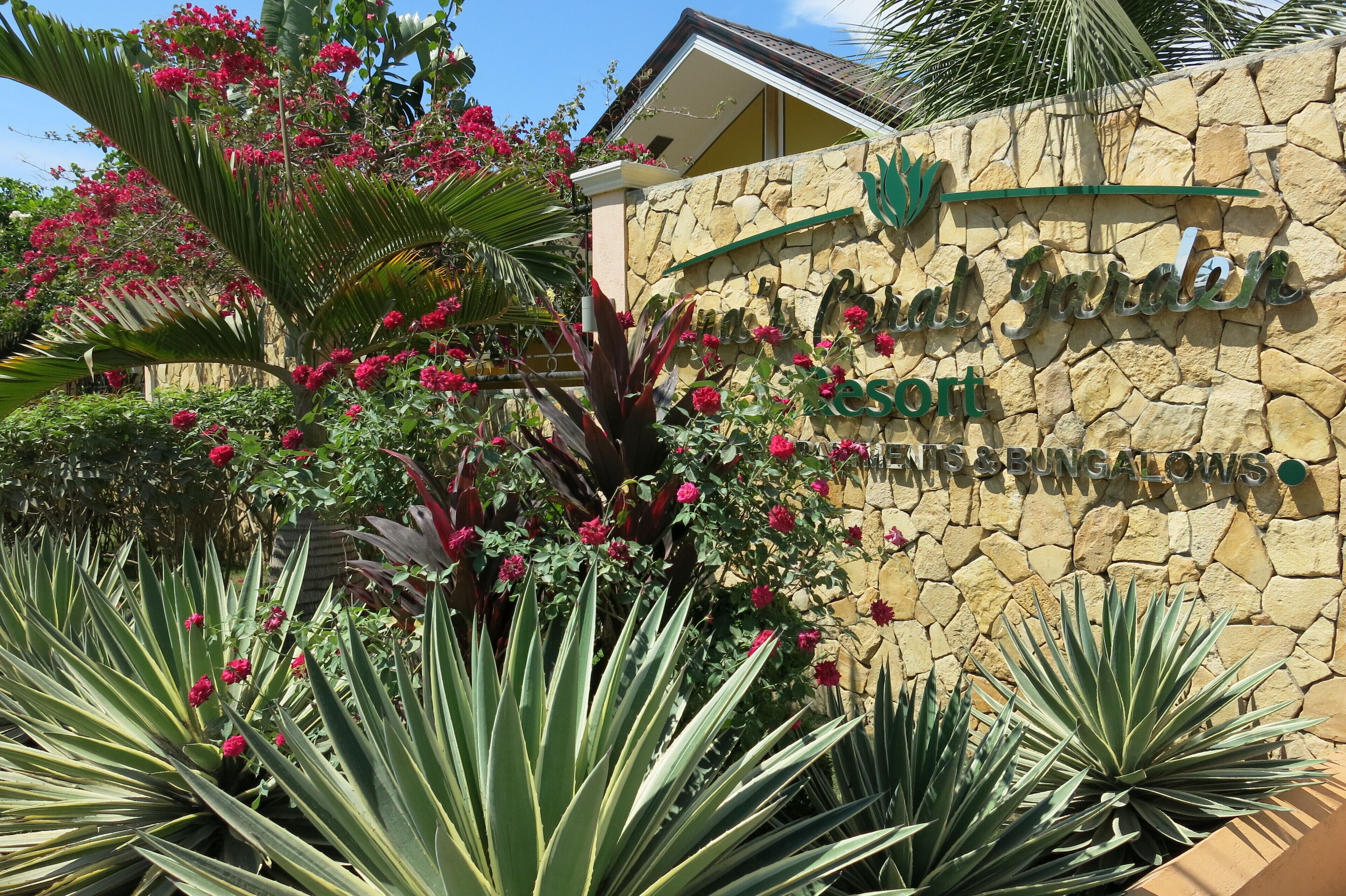 A stone wall with a sign for "Royal Garden Resort" and mentions "Houses & Bungalows".