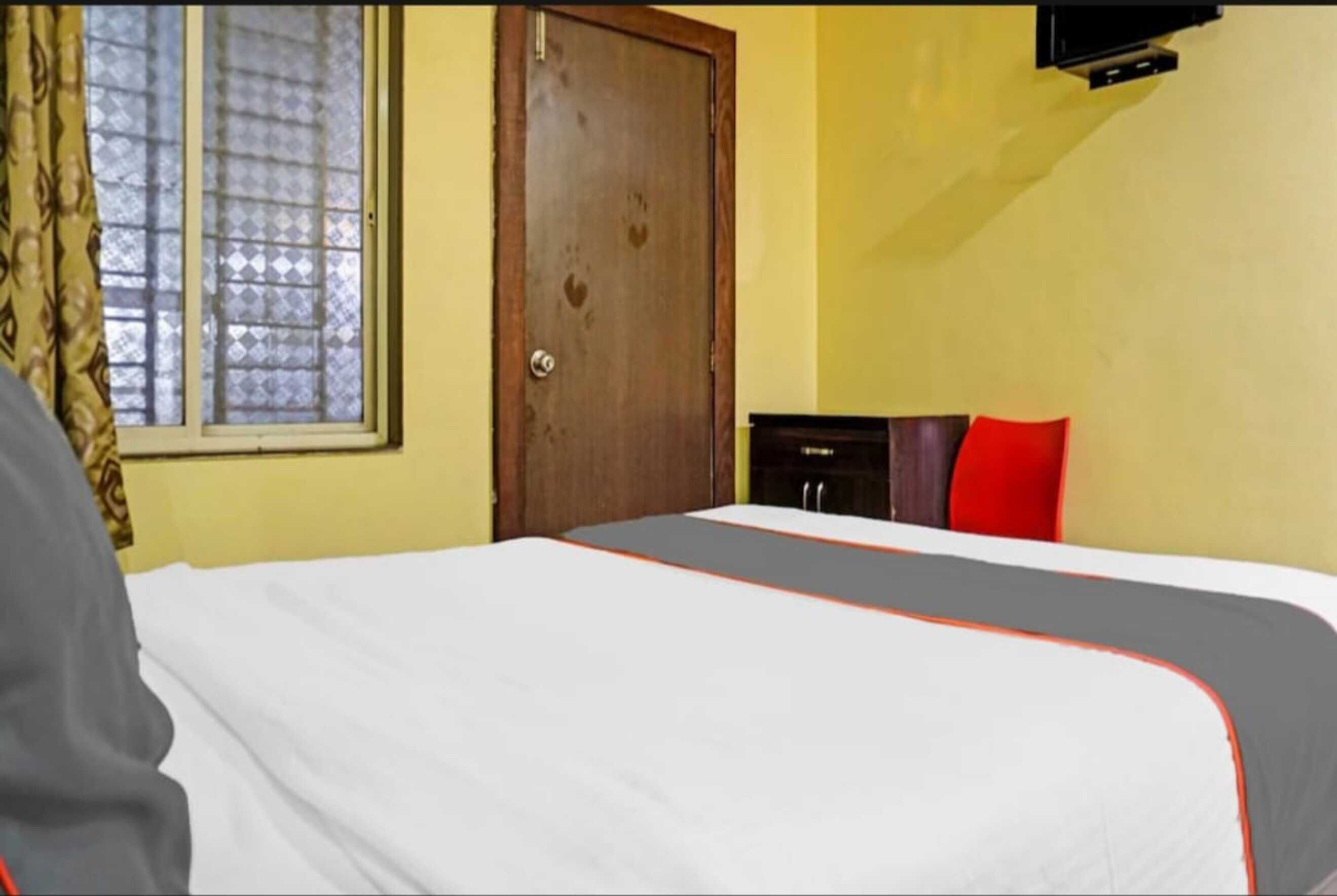 A hotel room with a bed, a wardrobe, a door, and a window with curtains.