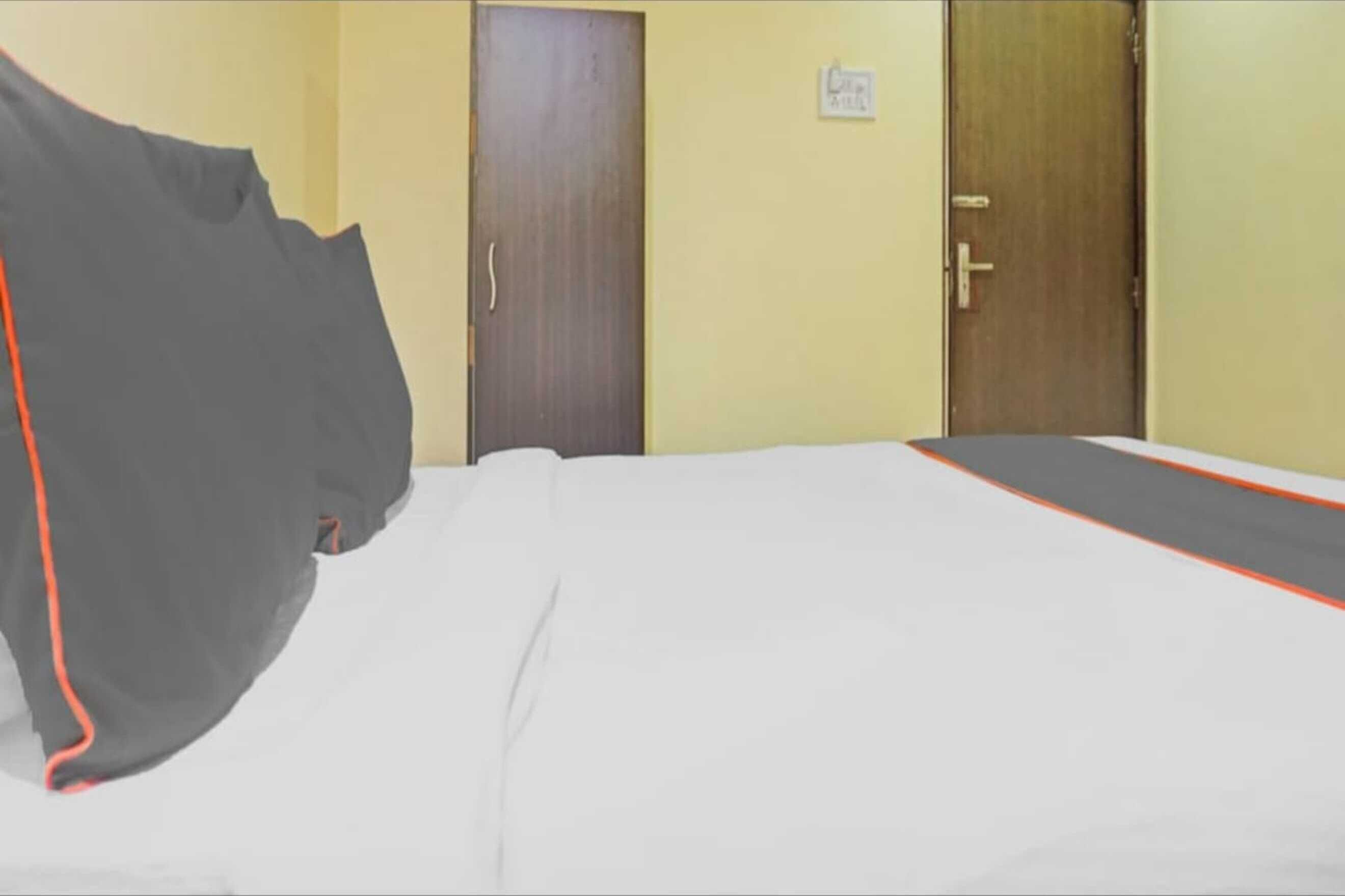 A hotel room with a bed, two doors, and a sign on the wall.