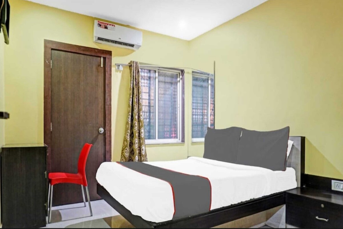 A room with a bed, a desk, a chair, and an air conditioning unit.