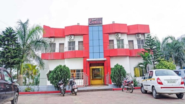 A building with a red and white facade, a central blue glass section, and a sign reading "Hotel Carnival." - Hotel Carnival (Rajgurunagar)