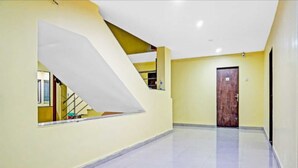 A hallway with a staircase, a door, and a window. - Hotel Carnival (Rajgurunagar)