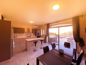 Enjoy meals in the kitchen with a central island and dining table for four, opening to a balcony with a hot tub and outdoor seating.
