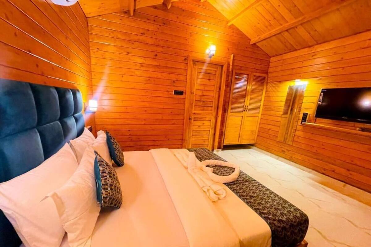 Une pièce de cabane en bois comprenant un lit, un téléviseur et un plafond en bois.