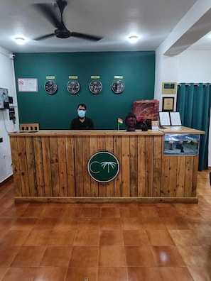 A reception desk with a wooden finish, a ceiling fan, and four wall clocks. - Coco Teros Resort (Mandrem)