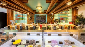 A dessert shop with a menu board, various jars of candies, and a selection of ice cream flavors.