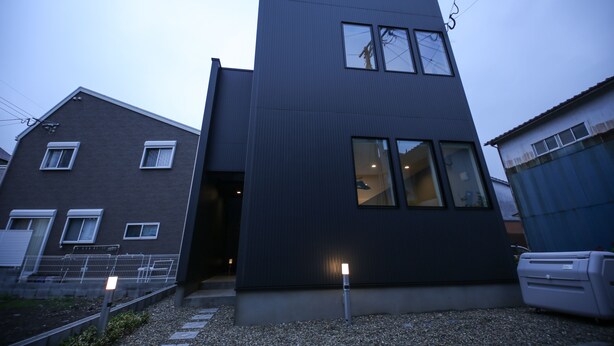 Un bâtiment moderne à deux étages, doté d’une façade sombre, de nombreuses fenêtres et d’une entrée bien visible.