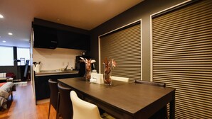 Une cuisine moderne avec un coin repas, comprenant une table en bois foncé, des chaises blanches et un vase avec des fleurs.