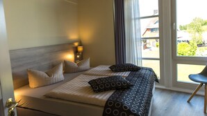 A hotel room with a large bed, a chair, and a view of the outside. - An der Metow-Ferienpark.Hotel (Plau am See)
