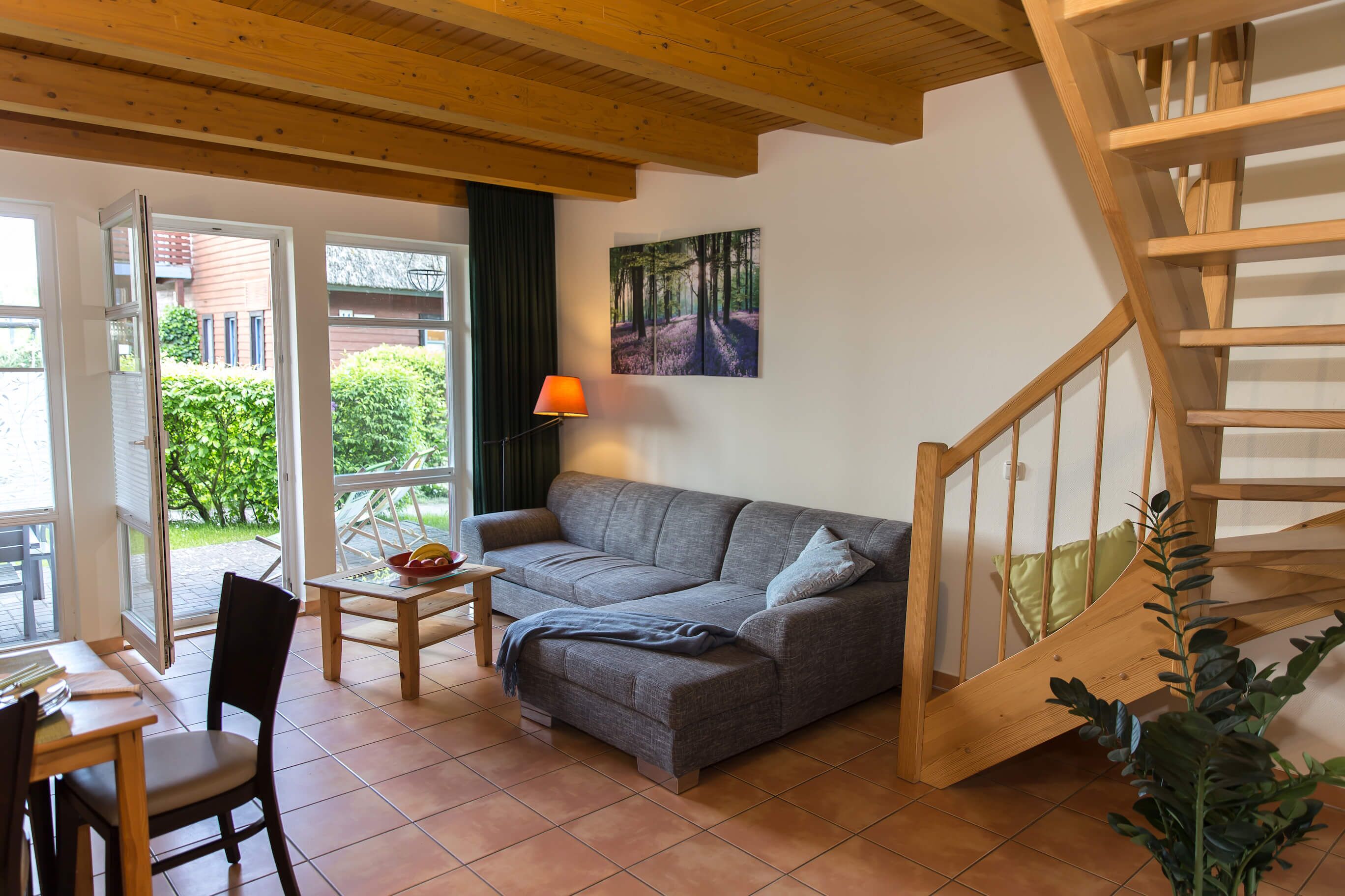 A living room with a sofa, a table, a chair, a lamp, and a staircase.