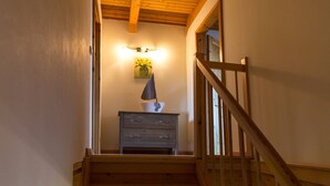 A wooden staircase with a railing leading to a landing. A small table with a lamp and a pineapple painting is on the landing. - An der Metow-Ferienpark.Hotel (Plau am See)