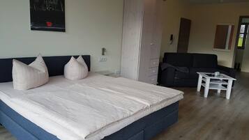 Ein Schlafzimmer mit einem großen Bett, einem Kleiderschrank, einer Couch und einem kleinen Tisch.