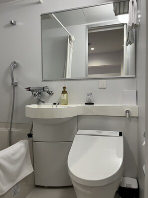 Un baño moderno con lavabo blanco, inodoro, ducha y espejo.