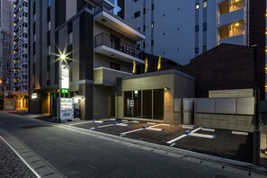 Una entrada de hotel moderna con un área de estacionamiento, una máquina expendedora y un letrero que indica estacionamiento en el segundo piso.