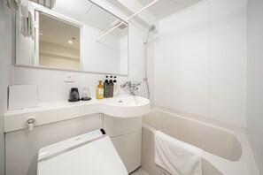 A modern bathroom with a white sink, a mirror, a handheld showerhead, and a towel rack. - Hotel Reference Hakata Reisen (Fukuoka)