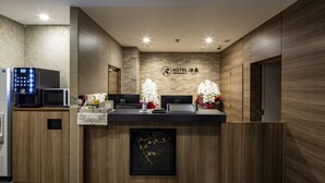 A hotel reception desk with a modern design, featuring a wooden finish, a digital display, and a framed artwork. - Hotel Reference Hakata Reisen (Fukuoka)