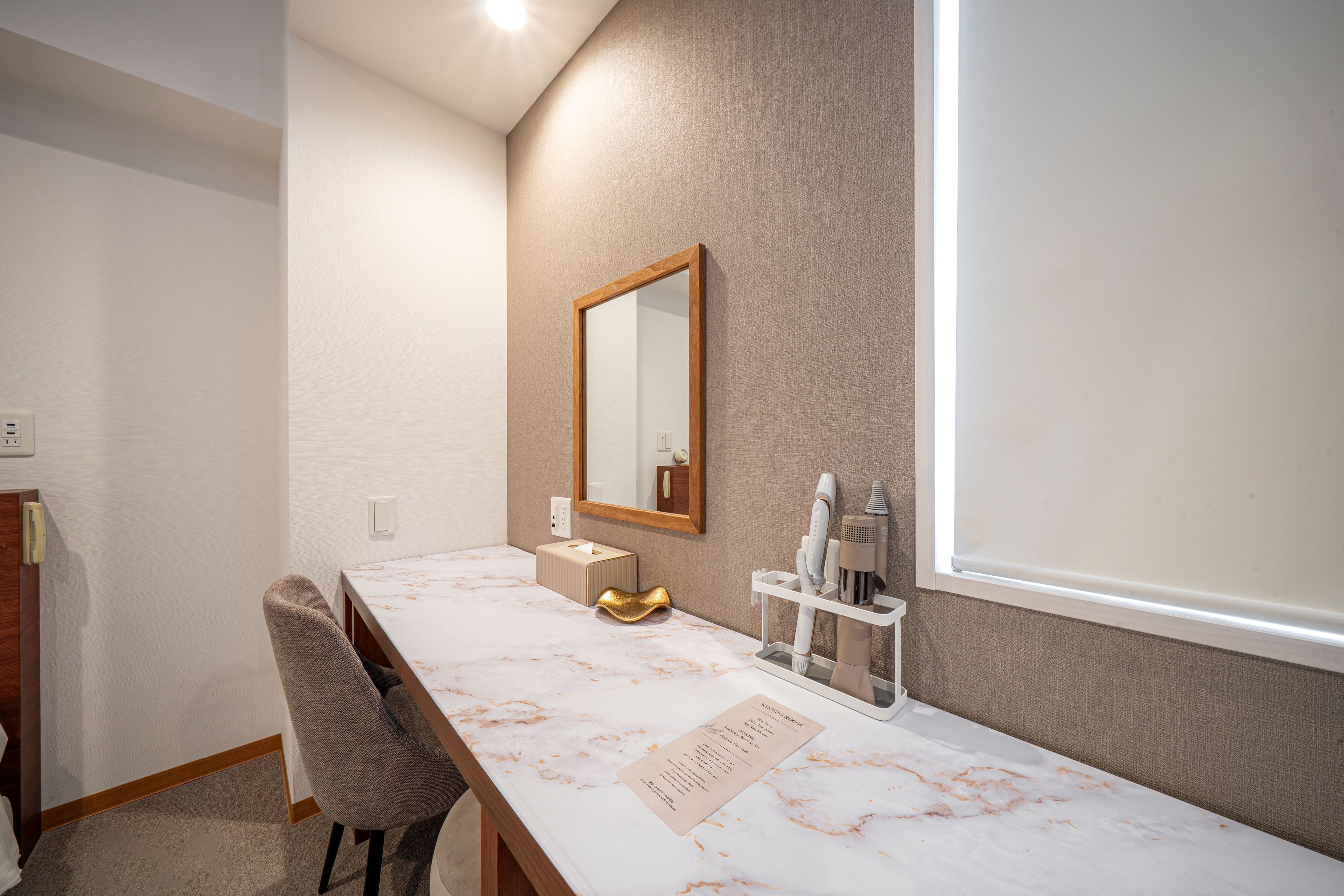 A hotel room with a marble vanity, a mirror, a towel, and a wall-mounted hairdryer.