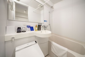 Een moderne badkamer met een wit wastafelmeubel, spiegel en douche. Er staan toiletartikelen op het aanrecht en een handdoek hangt aan de muur.