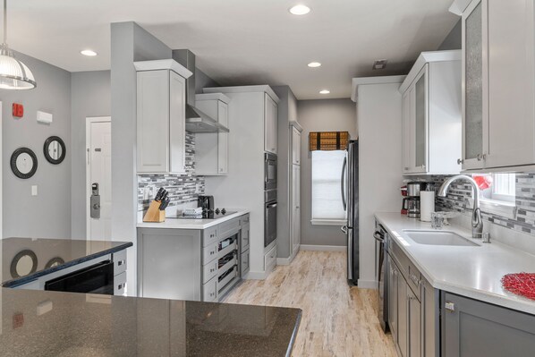 Enjoy cooking in this well-equipped kitchen with a central island, stainless steel appliances, and a tiled backsplash.