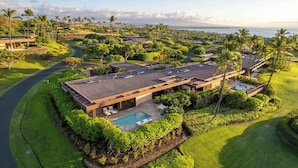 A modern resort with a pool, lush landscaping, and views of the ocean. - Villas at Mauna Kea 14 Two Bedroom (Kamuela)