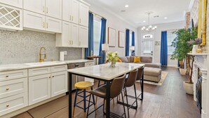 A modern kitchen with white cabinets, a marble countertop, and a dining area with a table and chairs. - Insta Ready Meets Modern Comfort - Stylish 2BD/2BA (New Orleans)