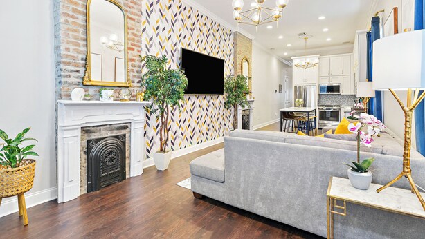 A modern living room with a fireplace, a grey sofa, and a TV mounted on the wall. - Insta Ready Meets Modern Comfort - Stylish 2BD/2BA (New Orleans)