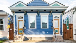 A two-story house with a blue exterior, numbered 2212 and 2214, featuring a front porch with steps and a small brick foundation. - Insta Ready Meets Modern Comfort - Stylish 2BD/2BA (New Orleans)