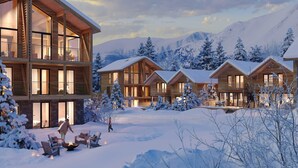 A modern log cabin hotel with multiple wooden structures, large windows, and a snowy landscape.