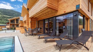 Ein Holzgebäude mit Pool, Liegestühlen und Essbereich.