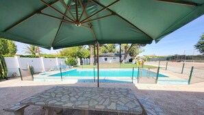 Eine Steinterrasse mit Pool und Sonnenschirm.