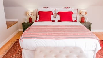 A neatly made bed with a patterned bedspread, two red pillows, and a matching bench.