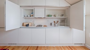 Een moderne keuken met witte kasten, een houten aanrechtblad en diverse keukenapparaten.
