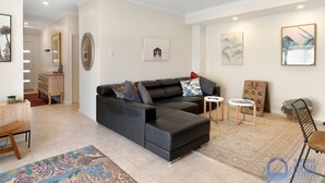 A modern living room with a black sectional sofa, a coffee table, and a patterned rug. - Summer Breeze at Avalon Beach (Wannanup)