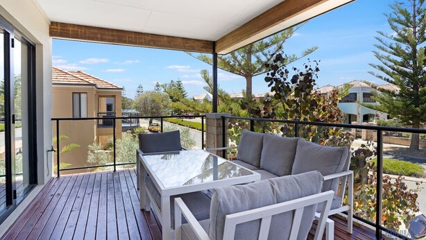 A balcony with a glass table and white furniture, overlooking a residential area with trees and houses. - Summer Breeze at Avalon Beach (Wannanup)