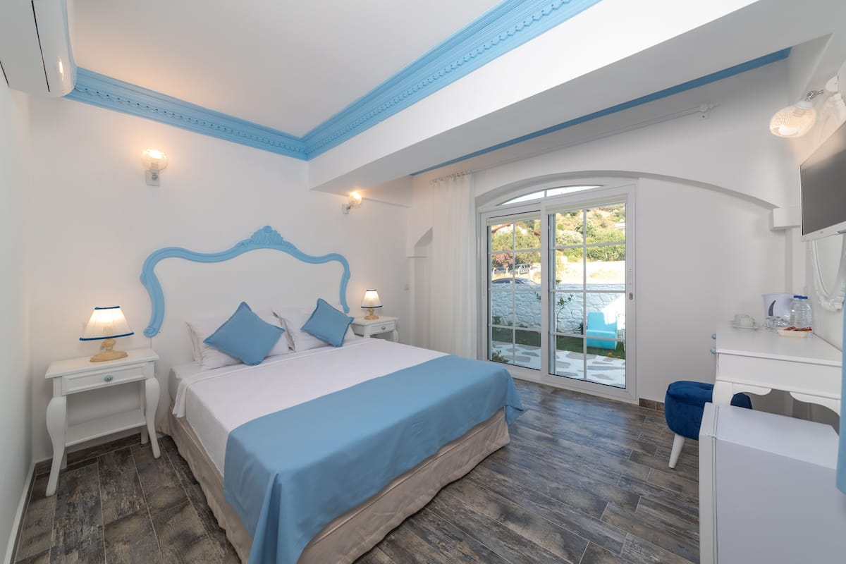 A bedroom with a bed, bedside tables, a desk, and a large window.