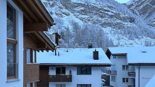 A snow-covered mountain landscape with buildings in the foreground. - Cozy attic apartment with charm - & private balcony (Zermatt)