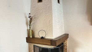 A corner room with a stone fireplace, a small bench, and a patterned rug. - Cozy attic apartment with charm - & private balcony (Zermatt)