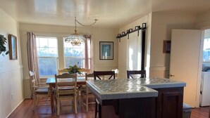 A kitchen with wooden flooring, a dining area with chairs, a chandelier, and a view through the window. - Classic 20th Century Architecture, Huge space for large families (Santa Maria)