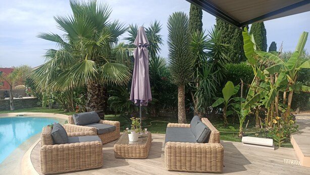 A poolside area with wicker furniture and a covered umbrella. - Pretty villa with sea view and pool **** (Bormes-les-Mimosas)