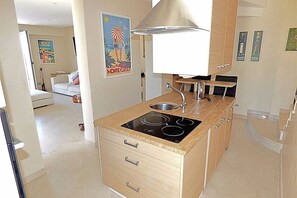 Une cuisine compacte équipée d’une cuisinière intégrée, d’un évier et d’un grand luminaire suspendu au plafond.