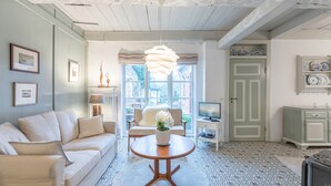 A living room with a sofa, a round wooden table, a hanging light fixture, and a television. - Vacation home Hus rode Dör for up to 5 people (Oldenswort)