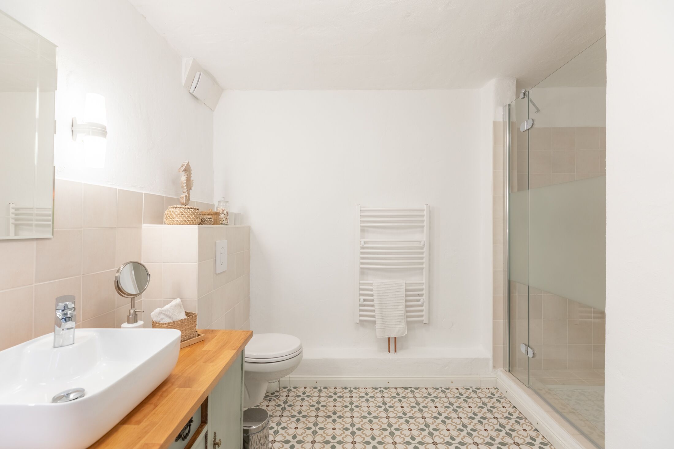 Une salle de bain avec un lavabo blanc, des toilettes et une cabine de douche en verre.