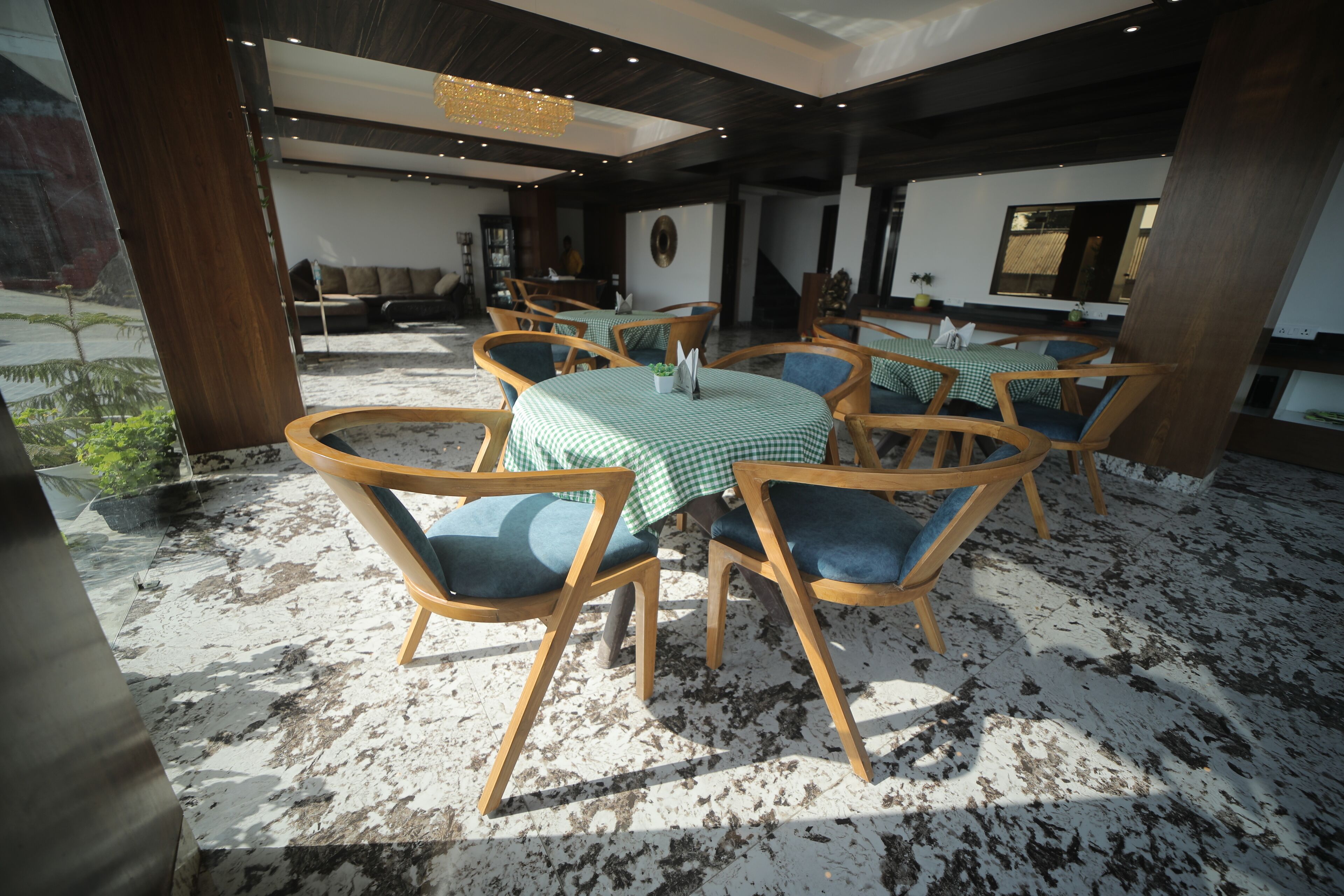 Un comedor con mesas redondas, sillas de madera y manteles a cuadros.